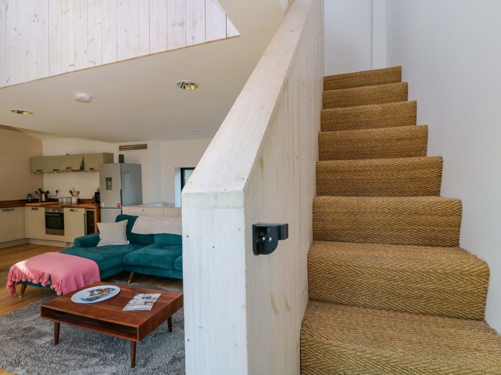A living room with staircase and kitchen area at 4 The Stoneyard Bath