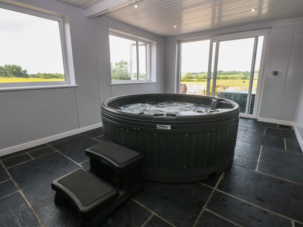 A hot tub in an indoor spa with windows at Morawelon in Pentraeth