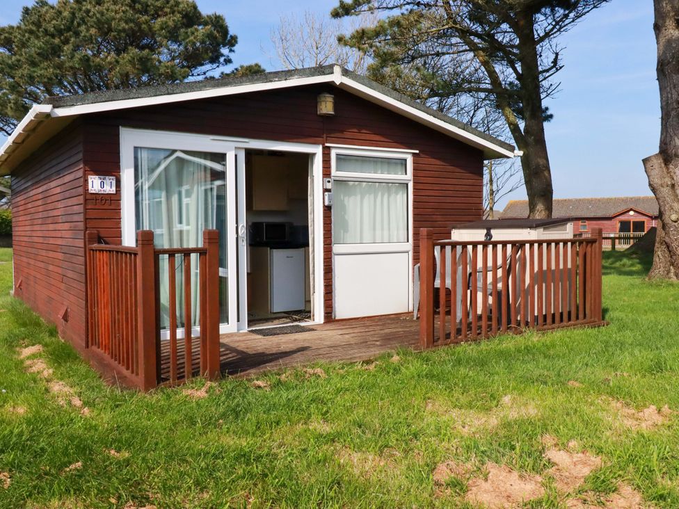 A cabin with a deck and trees at 101 Atlantic Bays Holiday Park in Padstow