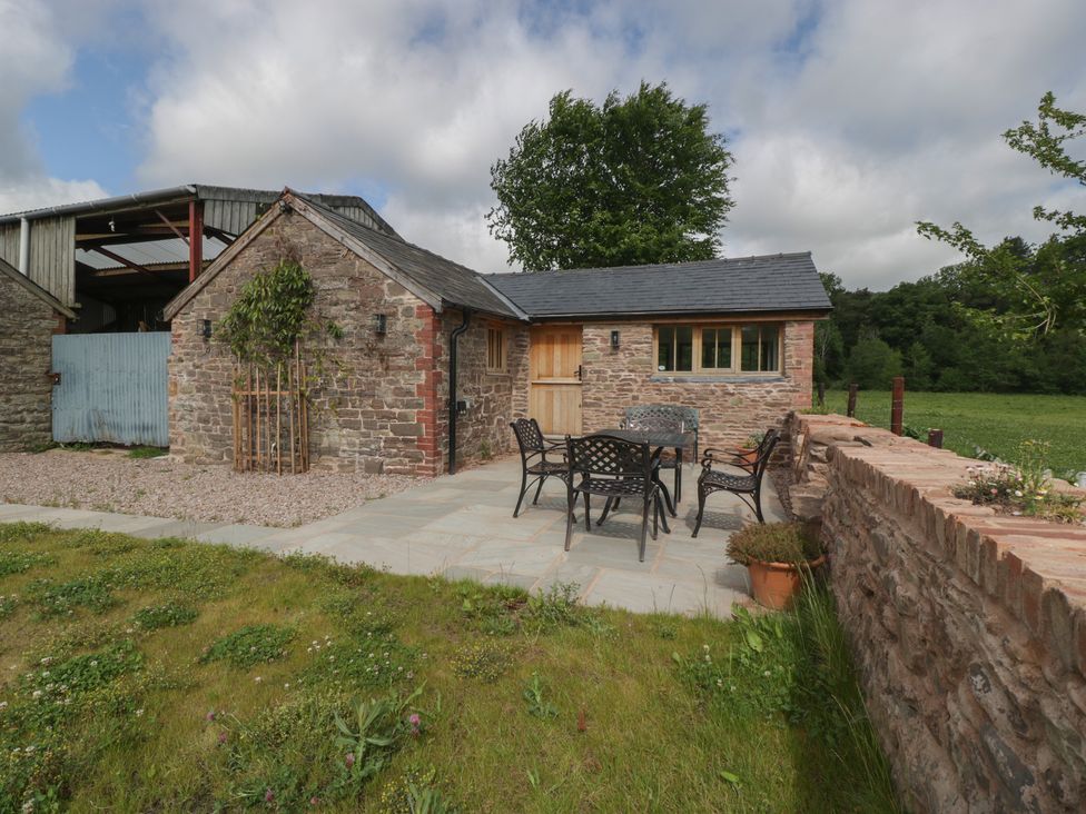An outdoor seating area with a table and chairs at Ynys Pandy near Ewyas Harold