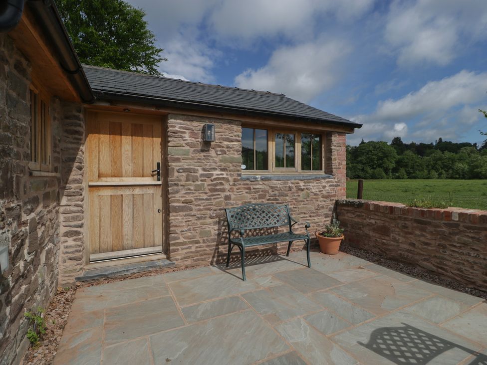 An outdoor area with a bench and door at Ynys in Pandy near Ewyas Harold