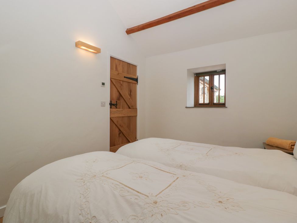 A bedroom with two beds and a wooden door at Ynys Pandy near Ewyas Harold