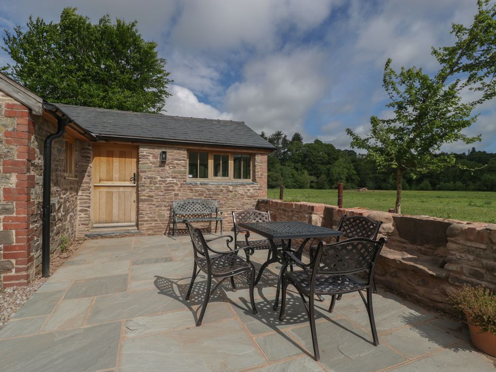 A patio with a table and chairs at Ynys Pandy near Ewyas Harold