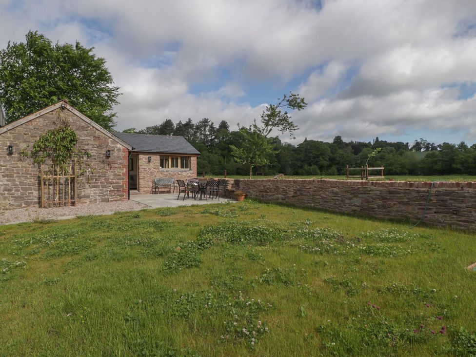 A garden with a building and outdoor seating at Ynys Pandy near Ewyas Harold