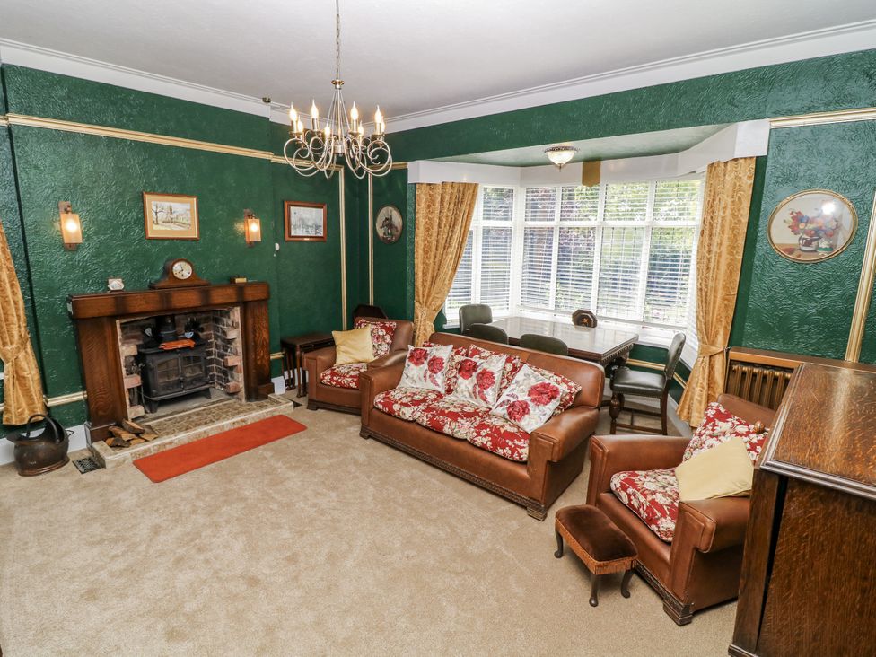A living room with a sofa, table, chairs, and a fireplace at Bentfield House, Rotherham near Whiston
