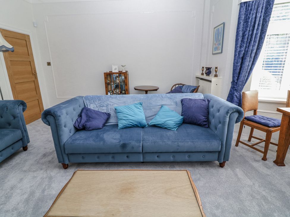 A living room with a blue sofa and wooden furniture at Bentfield House Rotherham near Whiston