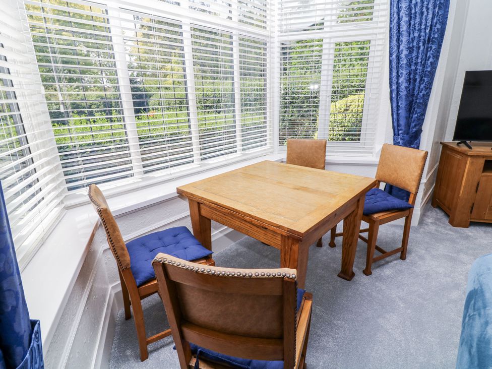 A table with four chairs in a sunroom with large windows at Bentfield House in Rotherham near Whiston
