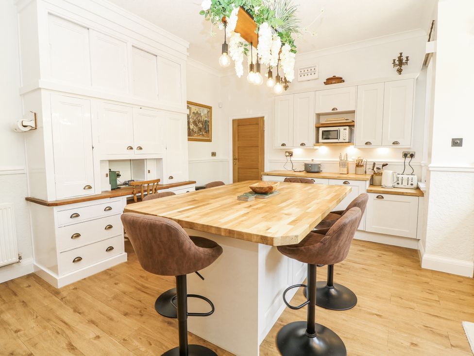 A kitchen with a wooden island and stools at Bentfield House in Rotherham near Whiston