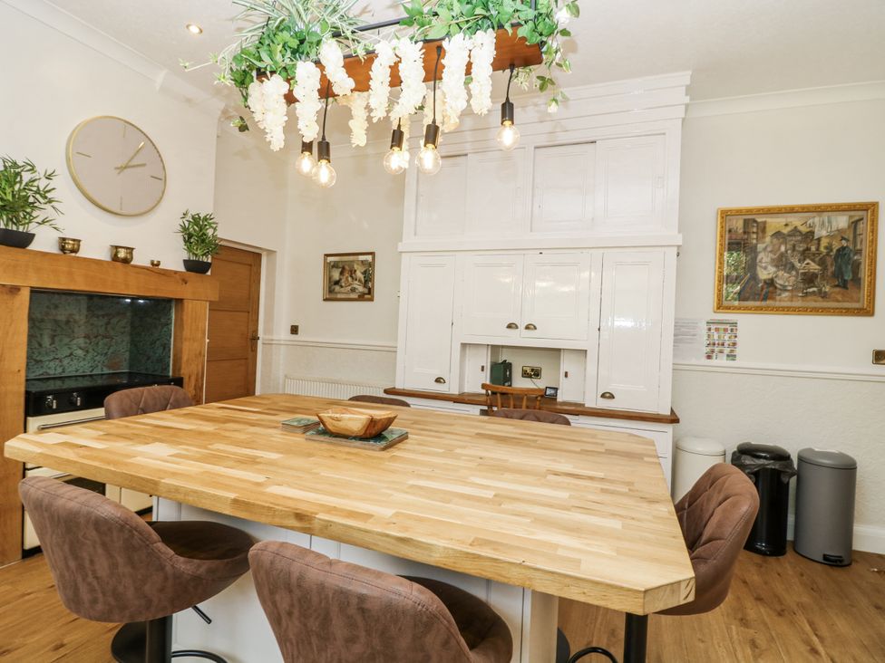 A kitchen with a wooden table and light fixtures at Bentfield House Rotherham near Whiston