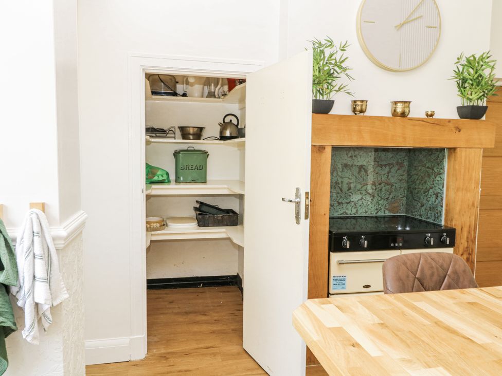A kitchen with a cooking stove and shelves in a pantry at Bentfield House Rotherham near Whiston