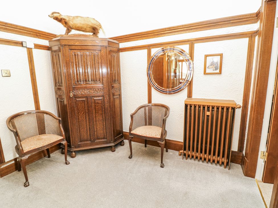 A hallway with a cabinet, chairs, and a mirror at Bentfield House in Rotherham near Whiston