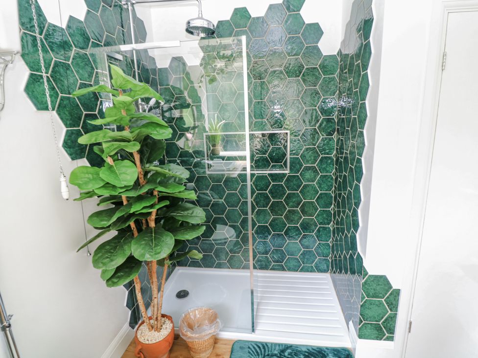 A shower with green tiles and a plant at Bentfield House in Rotherham near Whiston
