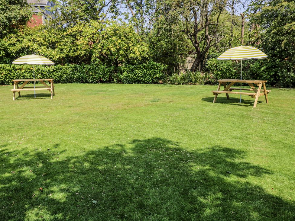 A garden with picnic tables and umbrellas at Bentfield House in Rotherham near Whiston