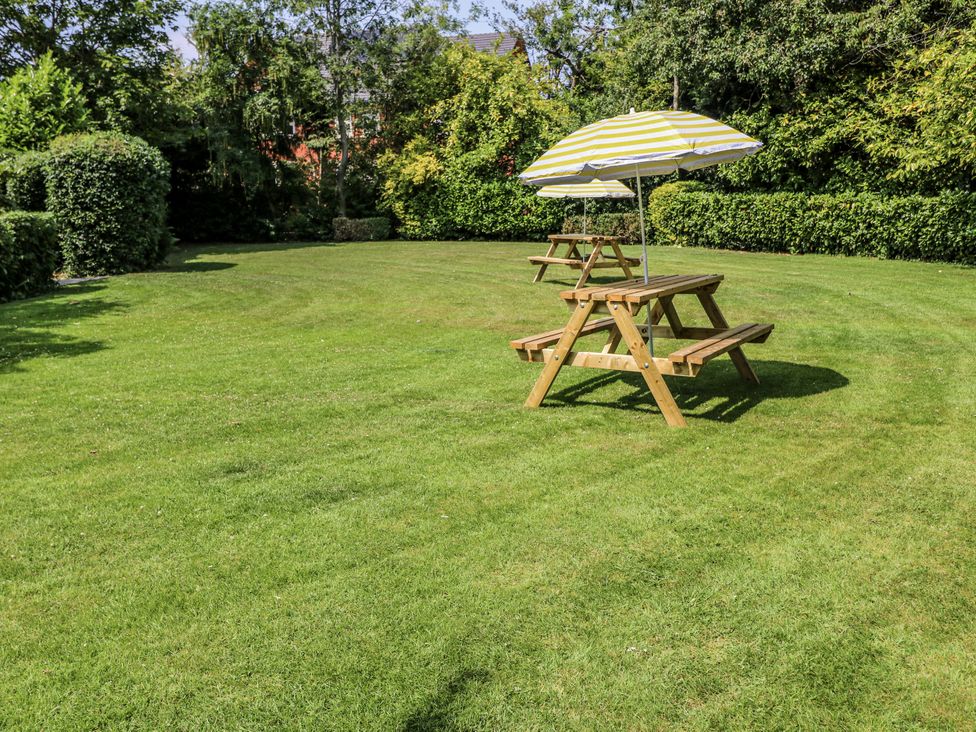 A garden with picnic tables and umbrellas at Bentfield House in Rotherham near Whiston