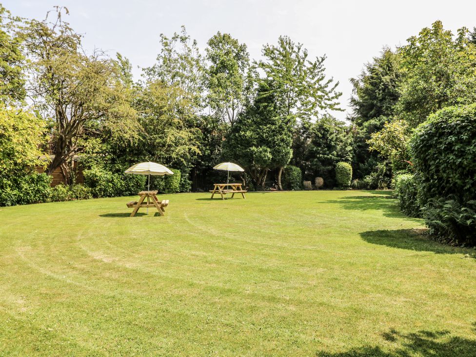 A garden with two picnic tables and umbrellas at Bentfield House in Rotherham near Whiston