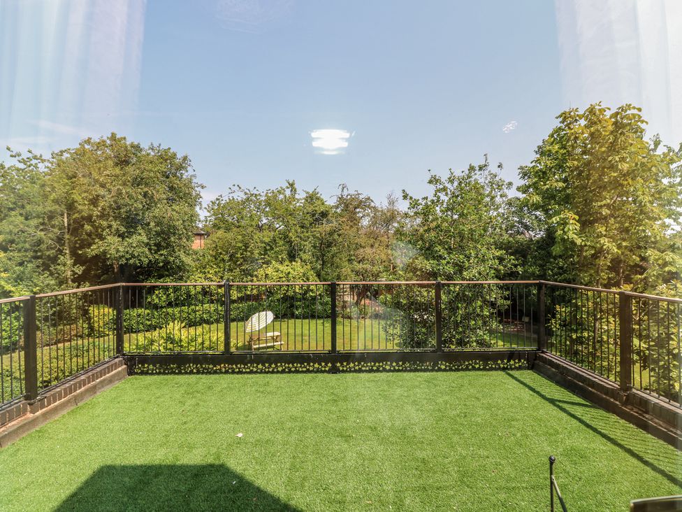 A balcony with artificial grass and a chair overlooking a garden at Bentfield House Rotherham near Whiston