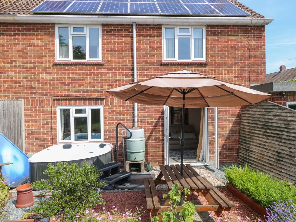 A garden with a hot tub and patio umbrella at 3 Birkbeck Way Norwich