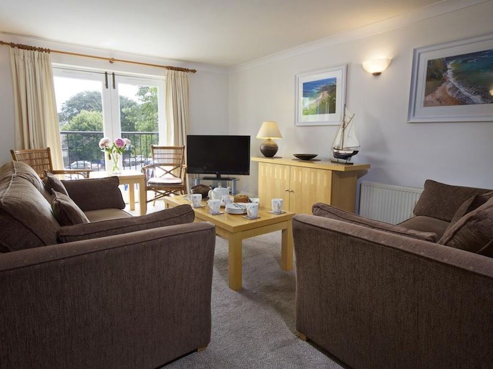 A living room with brown sofas a wooden coffee table a television and chairs at 10 Dartmouth House in Dartmouth