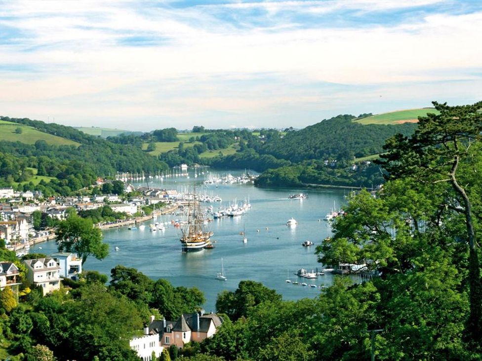A river with boats docked and houses along the shore surrounded by green hills and trees at 10 Dartmouth House in Dartmouth