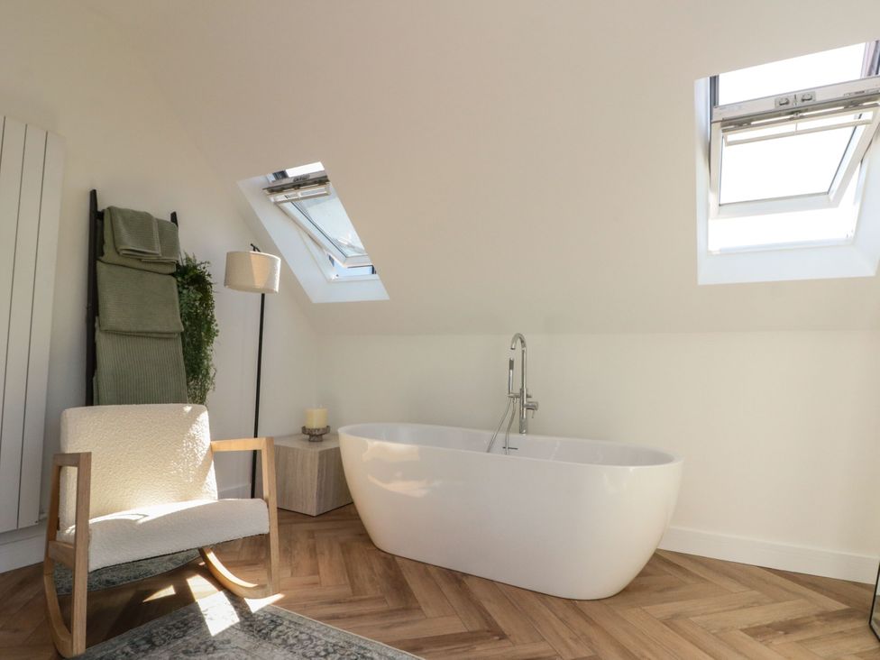 A bathroom with a bathtub and a chair at 12 Gap Road in Filey