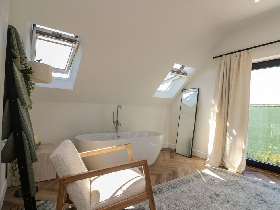 A bathroom with a bathtub and a chair at 12 Gap Road in Filey