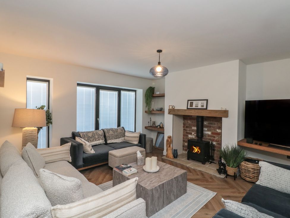 A living room with a fireplace and sofas at Puffin Lodge in Hunmanby