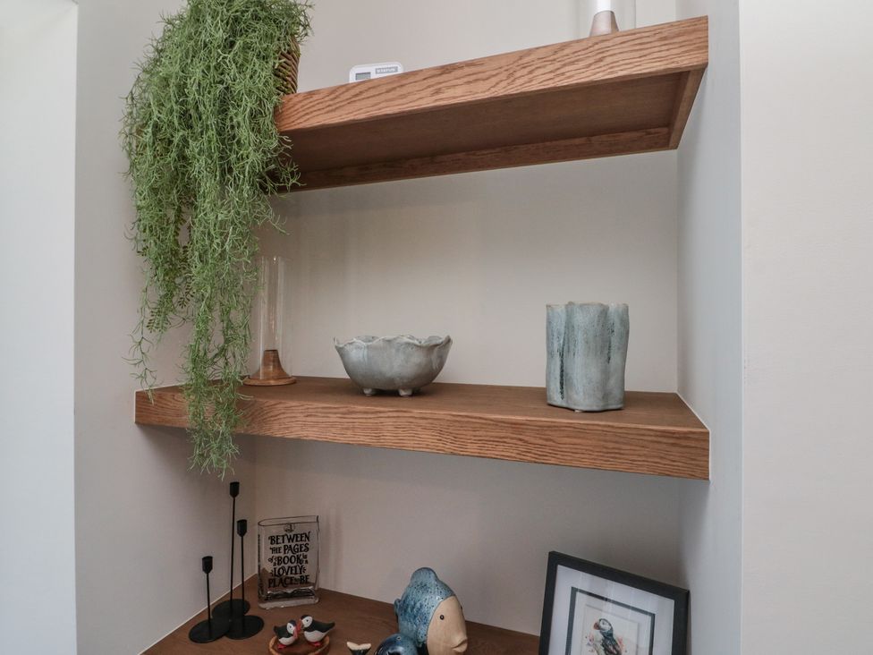 A shelf with decorative items and a plant at Puffin Lodge in Hunmanby