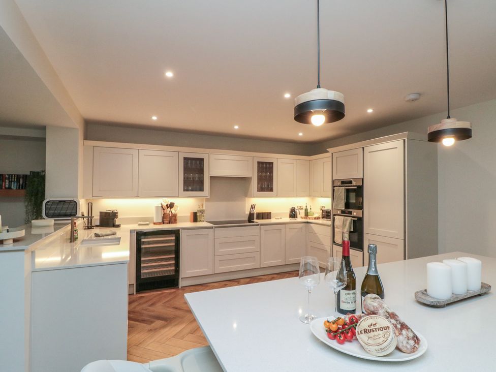 A kitchen with countertop, wine bottles, glasses, and food at Puffin Lodge in Hunmanby