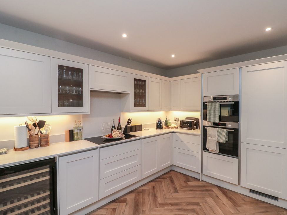 A kitchen with cabinets, appliances, and a countertop at Puffin Lodge in Hunmanby