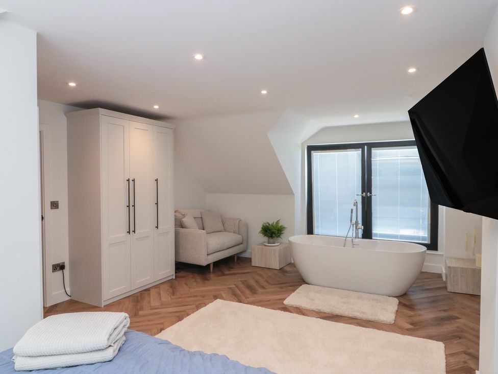 A bedroom with a bathtub and wardrobe at Puffin Lodge in Hunmanby