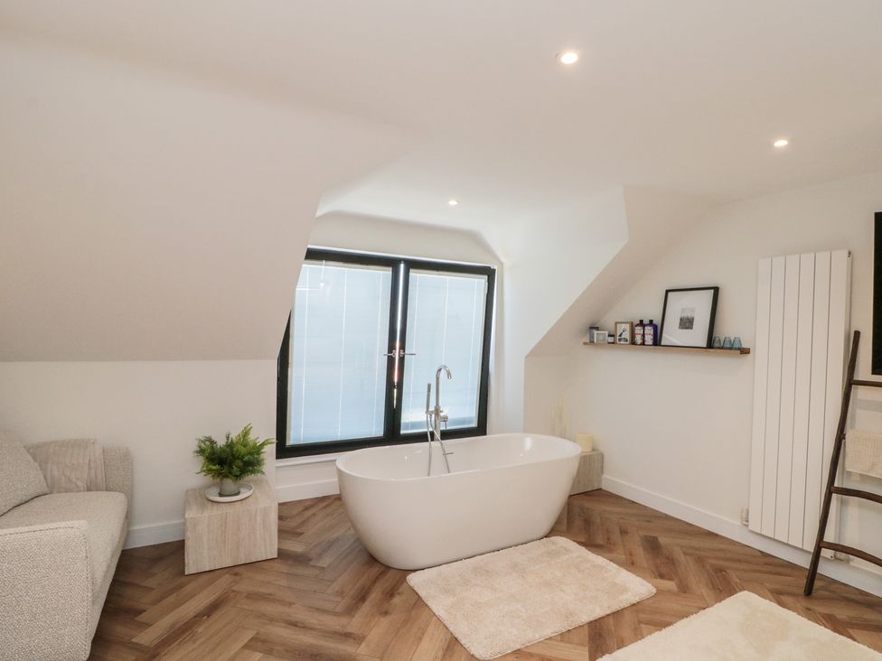 A bathroom with a bath tub and sofa at Puffin Lodge in Hunmanby