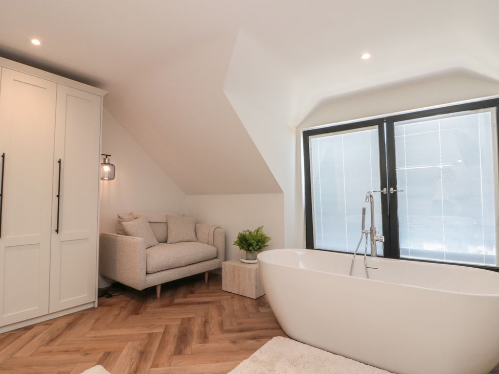 A bathroom with a bathtub and seating area at Puffin Lodge Hunmanby