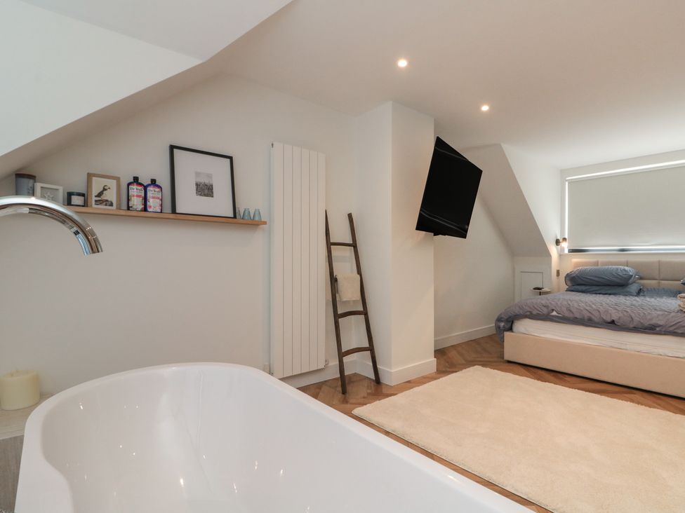 A bedroom with a bathtub and a bed at Puffin Lodge in Hunmanby