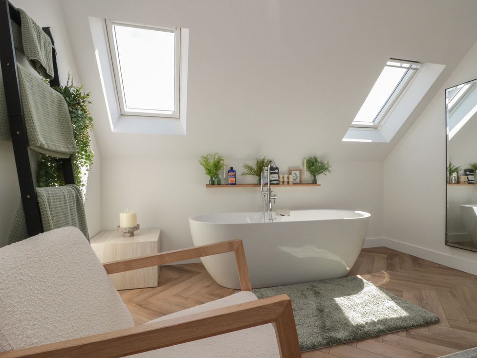 A bathroom with a bathtub and towel rack at Puffin Lodge in Hunmanby
