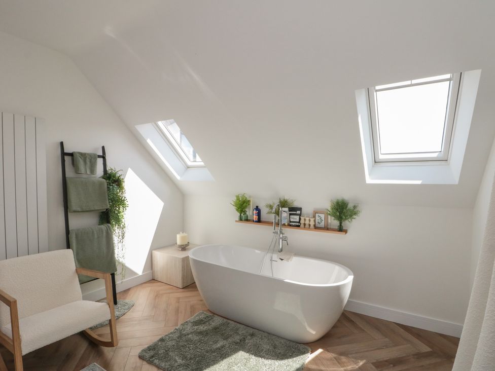 A bathroom with a bathtub and a shelf with plants at Puffin Lodge in Hunmanby
