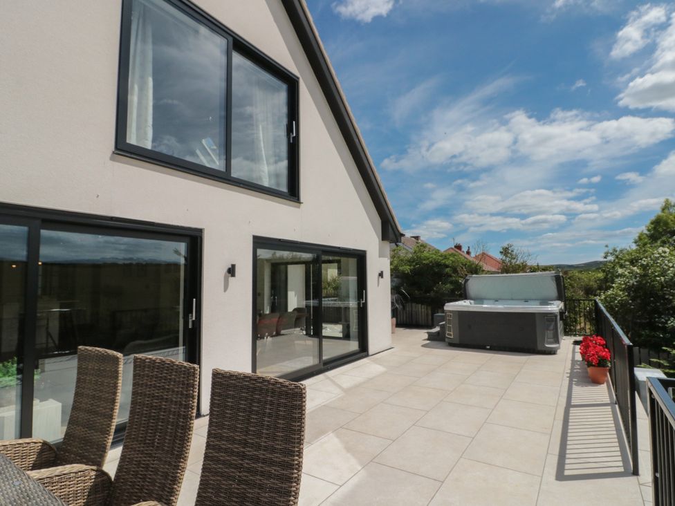 An outdoor patio with a hot tub and seating area at Puffin Lodge Hunmanby