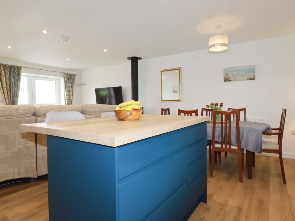 An open plan living area with a kitchen island and dining table at Folly View in Cambrose near Illogan