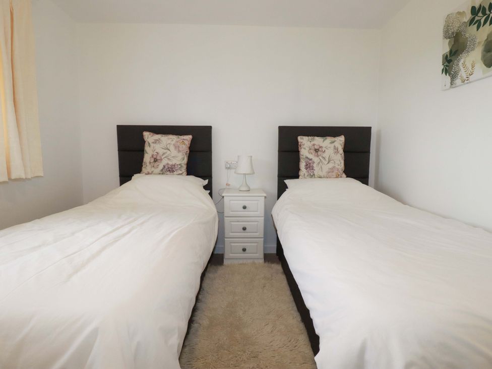 A bedroom with two single beds and a bedside table at Folly View Cambrose near Illogan
