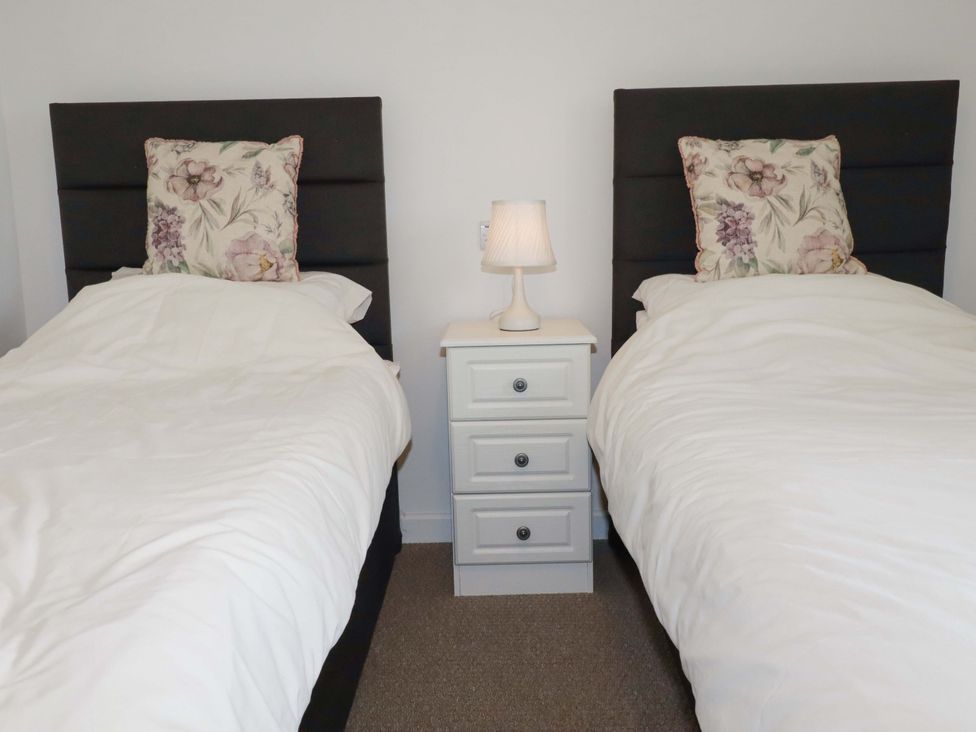 Two single beds with pillows and a nightstand in between at Folly View Cambrose near Illogan