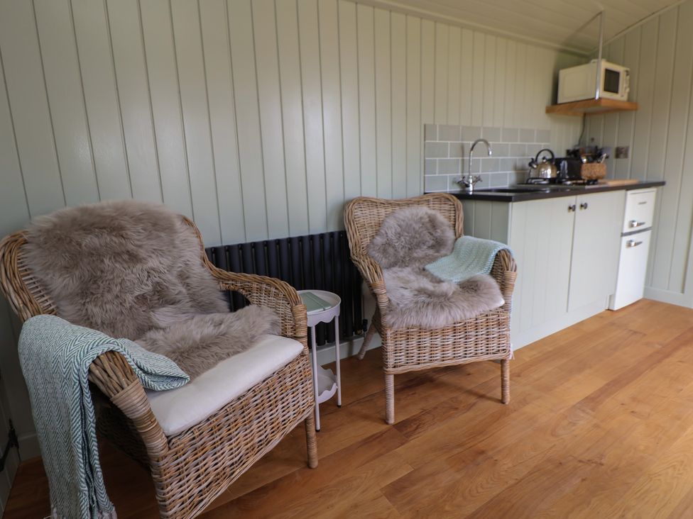 A seating area with chairs and kitchenette at Shepherd's Hut in Wrexham