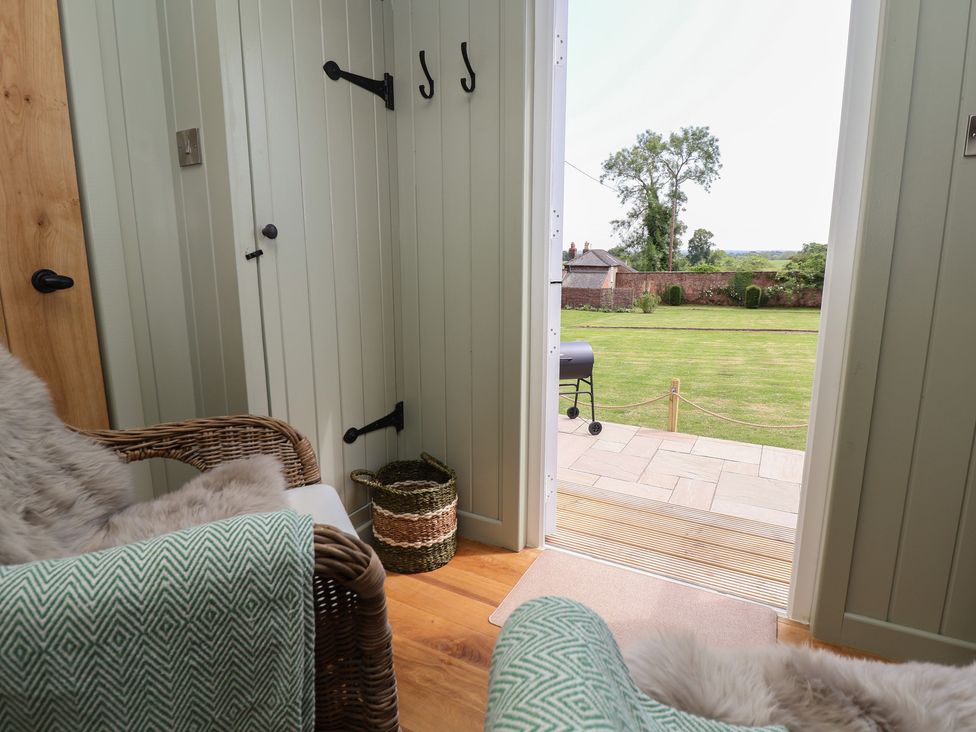A hallway with hooks and a chair at Shepherd's Hut in Wrexham