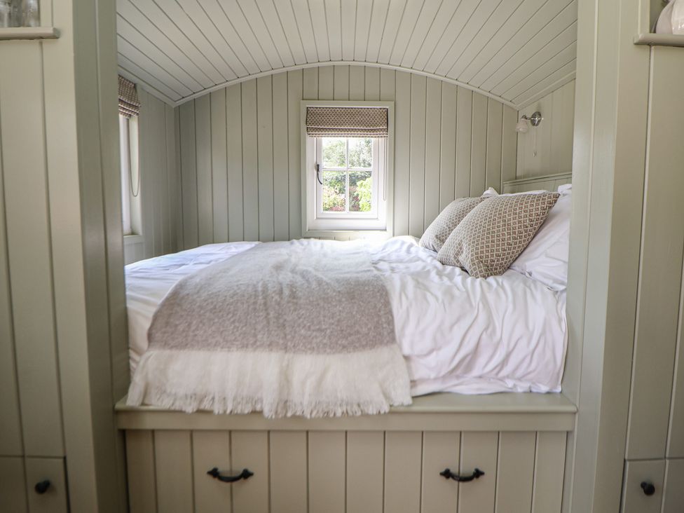 A bedroom with a bed and windows at Shepherd's Hut in Wrexham