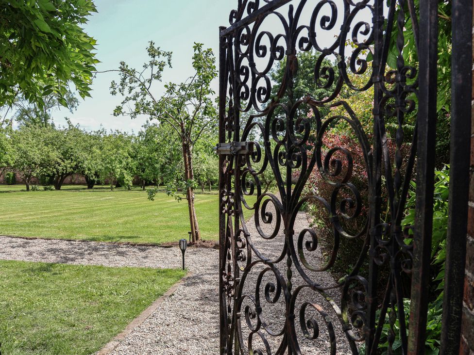 A garden view through a wrought iron gate at Shepherd's Hut in Wrexham