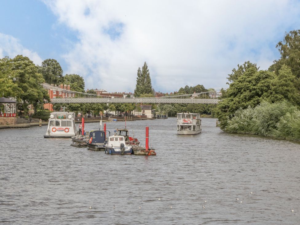 Boats on a river with a bridge in the background at The Garden Hut in Wrexham