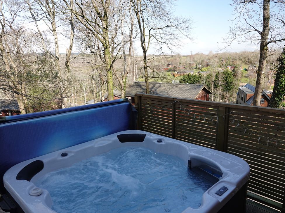A hot tub on a wooden deck overlooking a landscape at Acorn Lodge Finlakes Holiday Park near Chudleigh