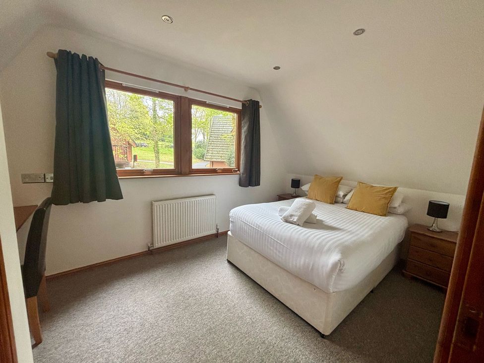 A bedroom with a bed, desk and window at Acorn Lodge Finlakes Holiday Park near Chudleigh
