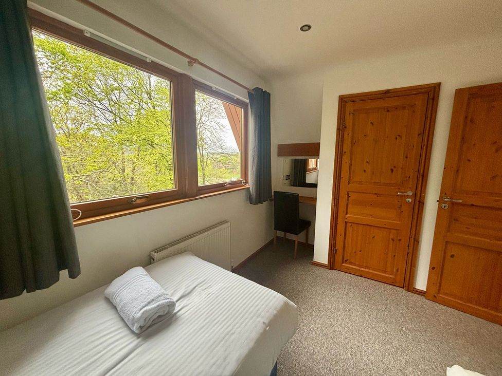 A bedroom with a bed and a desk at Acorn Lodge near Finlakes Holiday Park