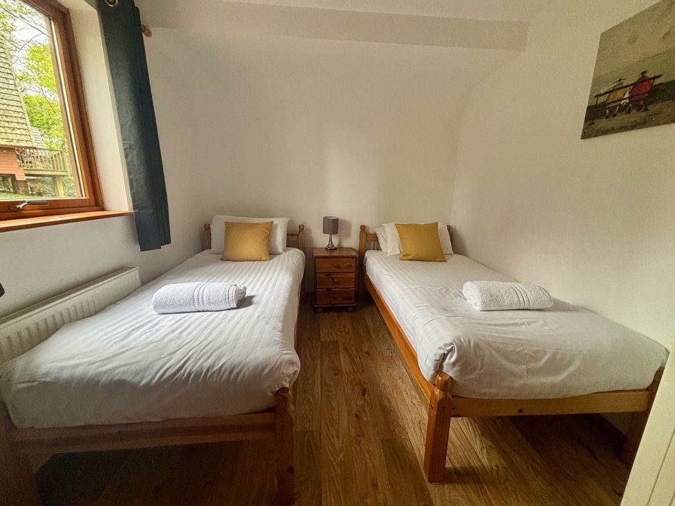 A bedroom with two single beds and a bedside table at Acorn Lodge Finlakes Holiday Park near Chudleigh