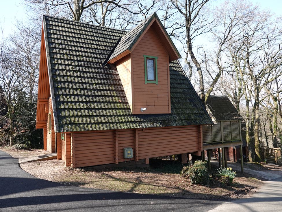 A wooden house with a sloped roof and deck at Acorn Lodge Finlakes Holiday Park near Chudleigh