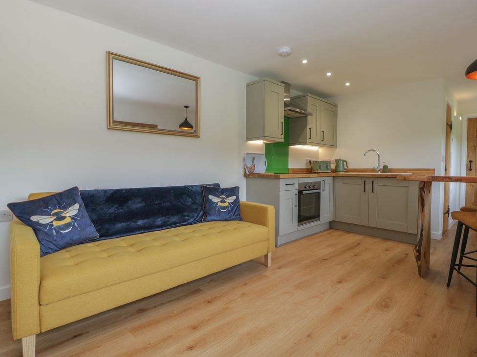 A living room with a sofa and kitchen area at Monnow in Pandy near Longtown (hereford)